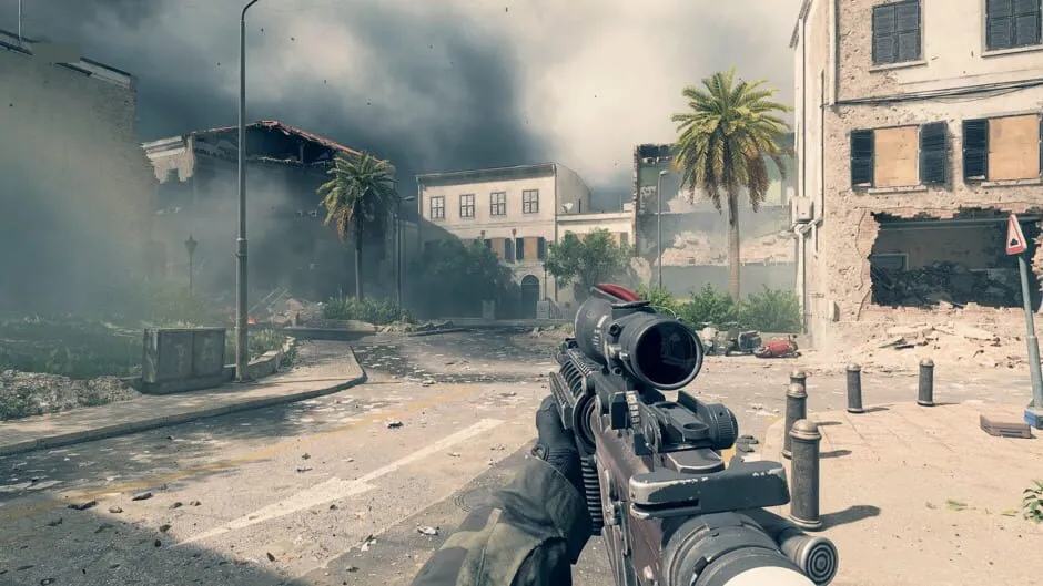 A first-person view of an assault rifle with a red dot optic on a bomb-damaged street lined with palm trees